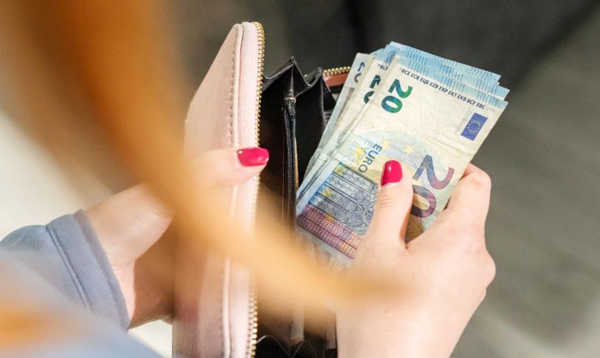 Una mujer saca varios billetes de su cartera