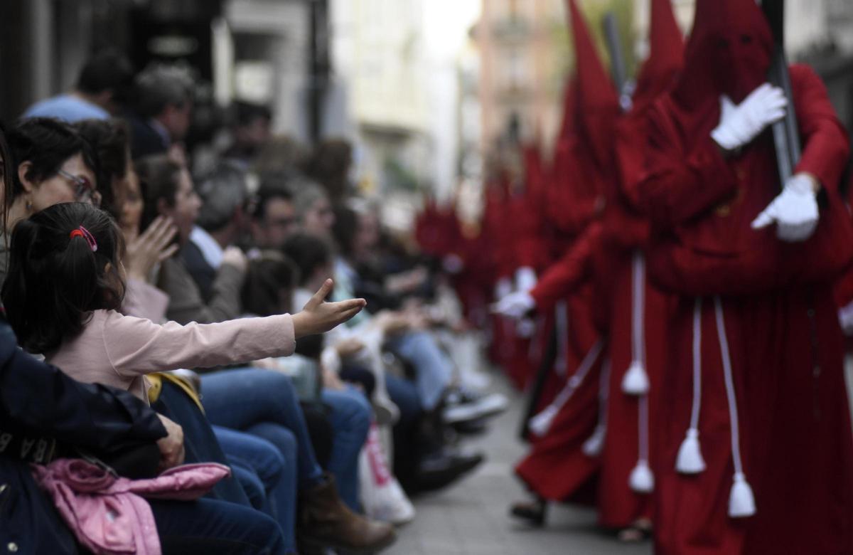 Una niña extiende la mano para pedir caramelos en la procesión de La Caridad en Murcia este 2024.