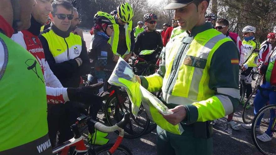 Un Guardia Civil entrega chalecos ayer en la rotonda de San Vicente de O Grove. // Muñiz