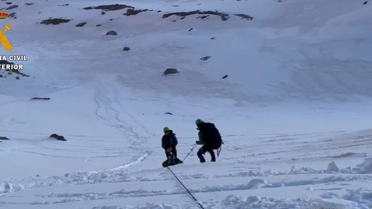 Dos efectivos de la Guardia Civil arrastran al herido en una camilla por la nieve.