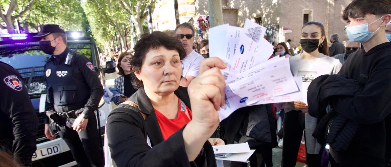 Una mujer muestra los boletos comprados para las sillas del Entierro junto a la Policía Local en la avenida Alfonso X.