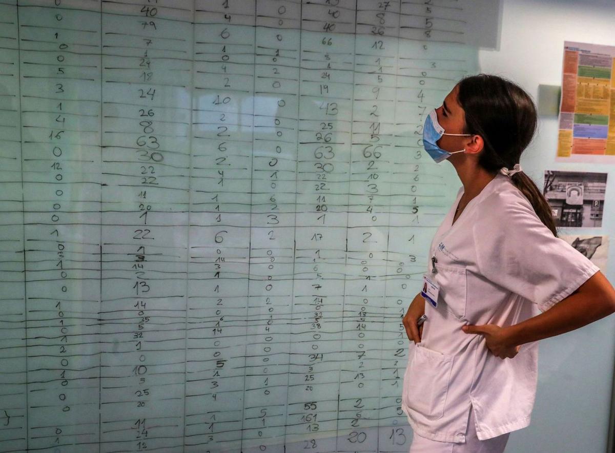 Una sanitaria observa un panel de cuadrantes de geriatría.