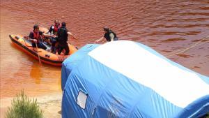 Miembros de los servicios de rescate navegan por el Lago Rojo mientras buscan nuevas pistas de los crímenes.