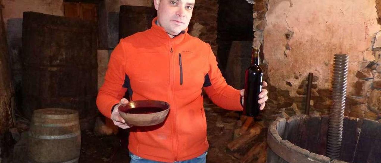 Javier Álvarez muestra un cachu y una botella de vino en su bodega, en Biescas.