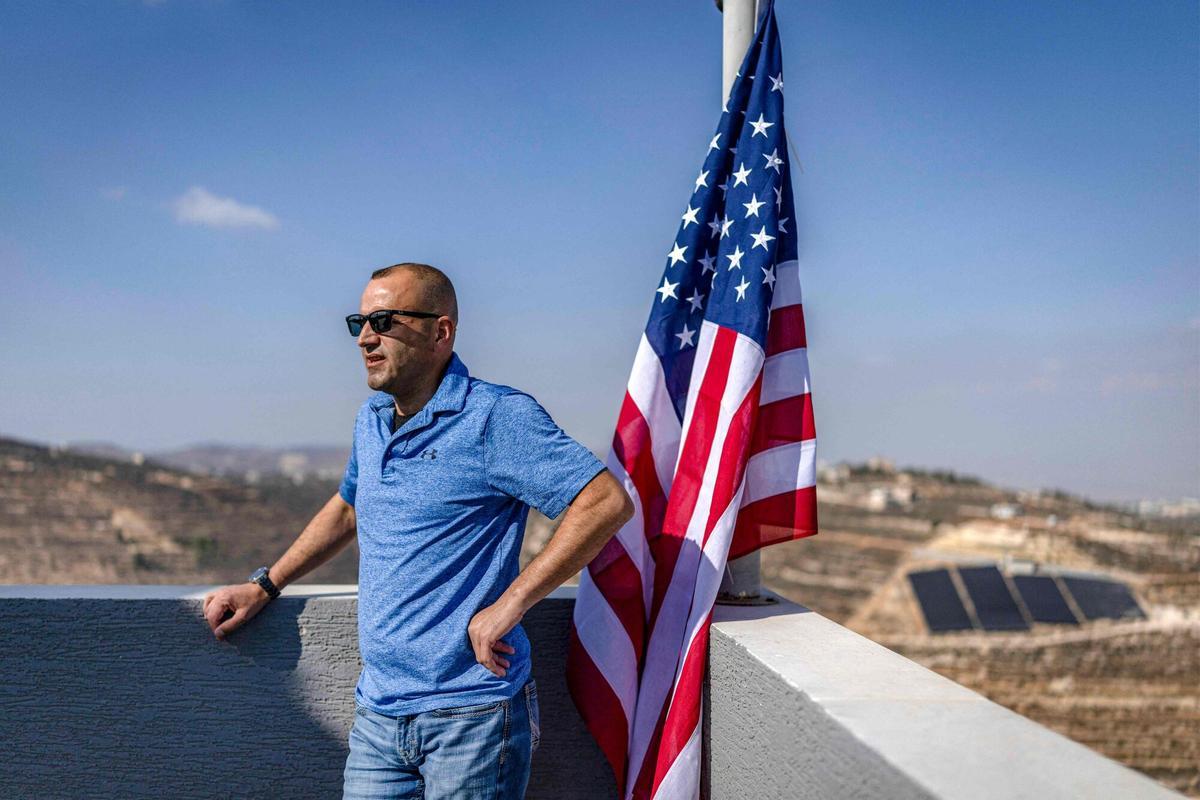 Loui Ridi, junto a la bandera de EEUU que ha colocado en el tejado de su vivienda en Qusra.