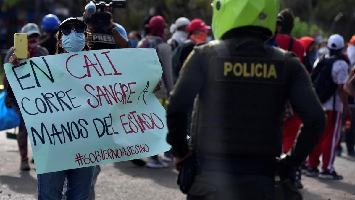 Una manifestante muestra un cartel a un policia durante una de las protestas del martes pasado en el barrio Siloe de la localidad colombiana de Cali