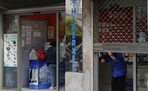 Una empleada de Hiperxel baja la verja de uno de los 10 locales de la compañía en Vigo.