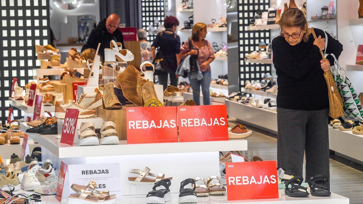 Una señora mira zapatos en rebajas en una tienda de Triana.