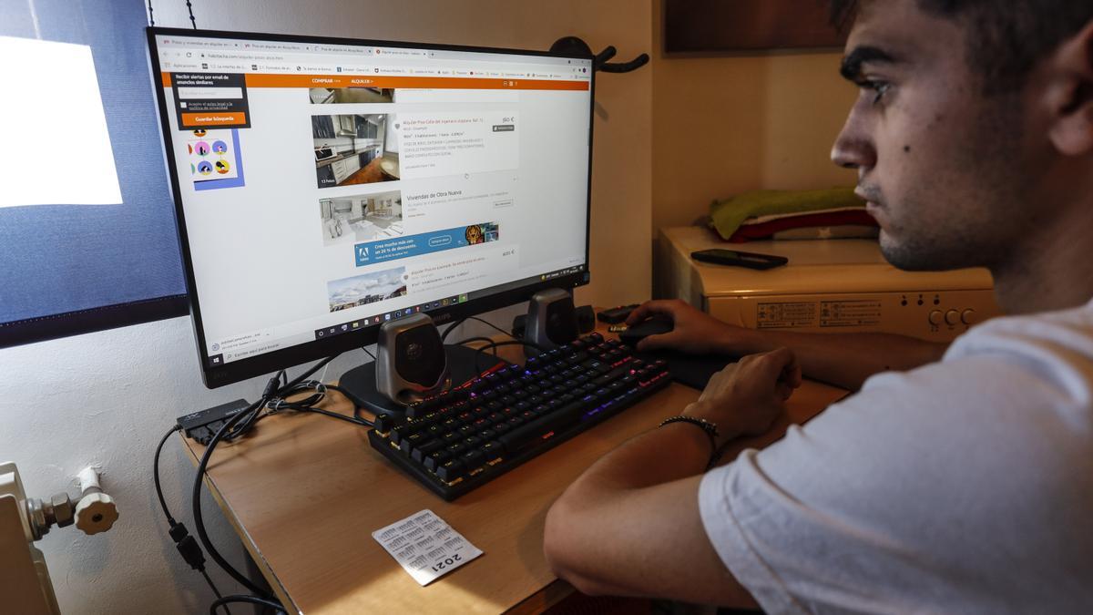 Un joven busca pisos de alquiler en portales inmobiliarios online.