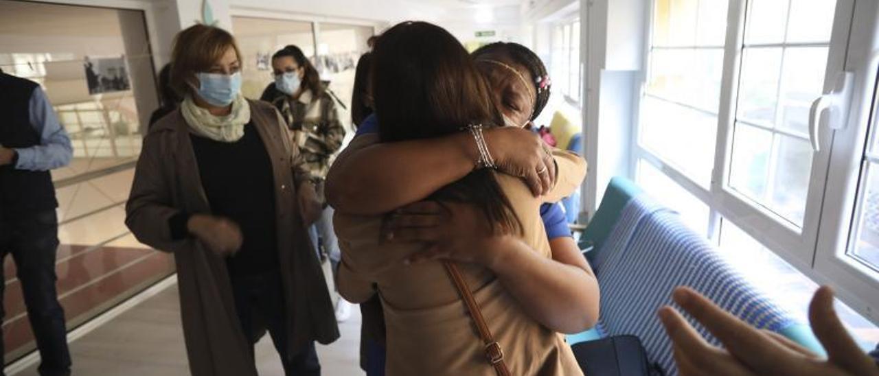 Queen Aduma abraza a Marisa González ante la Alcaldesa, ayer, en el centro de personas sin hogar. Arriba, en la que fue su habitación. | R. S.