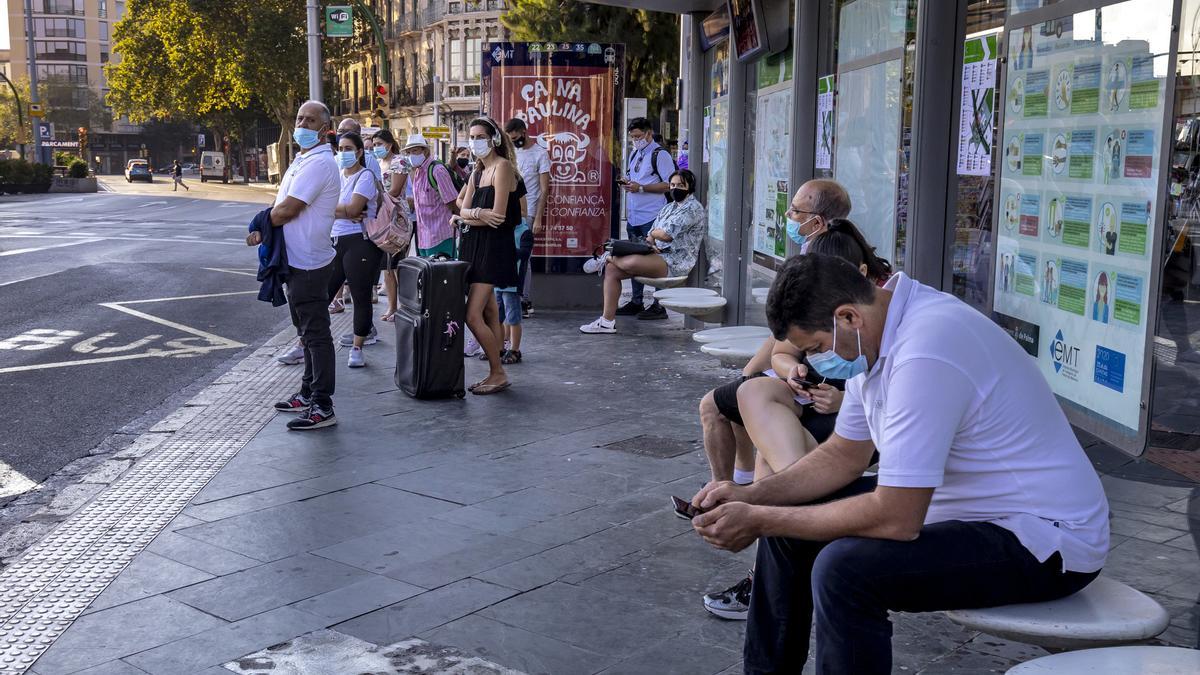 Ciudadanos esperan el autobús con la mascarilla puesta en la parada de la Plaza de España, en Palma