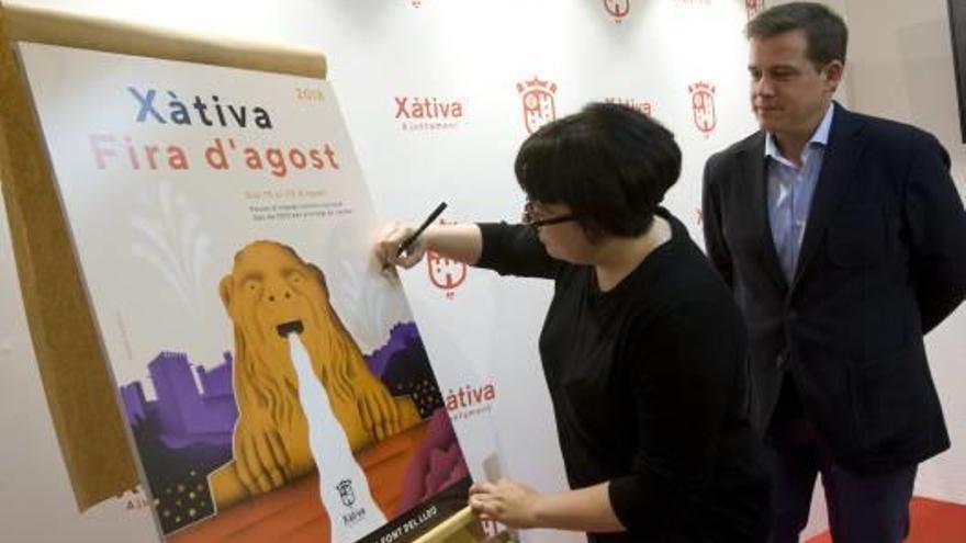 La diseñadora Malota firma el cartel ante el alcalde, Roger Cerdà, ayer tras la presentación.