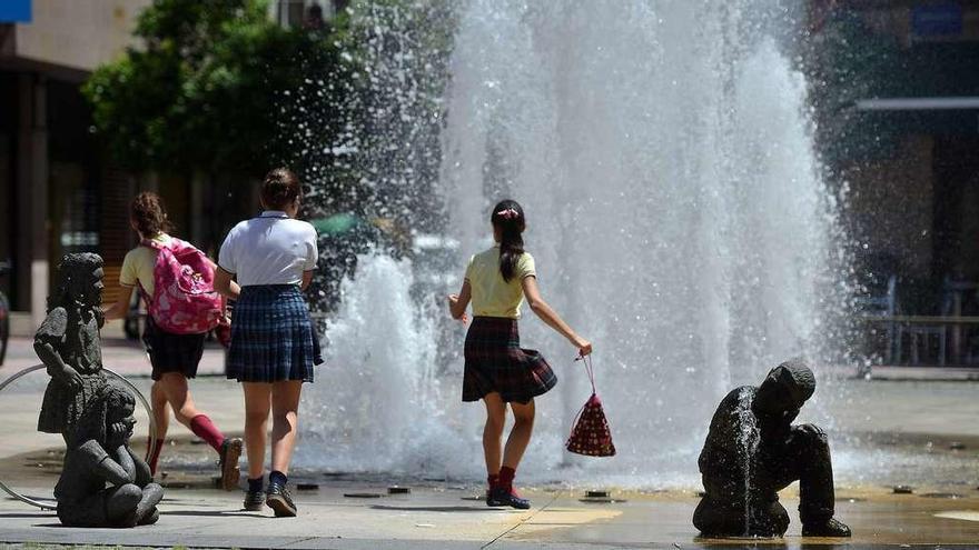 Unas niñas se refrescan con el agua de la fuente de la Glorieta de Compostela de Pontevedra en un día de calor esta primavera. // G. Santos