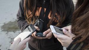 Tres chicas muestran sus teléfonos móviles. 