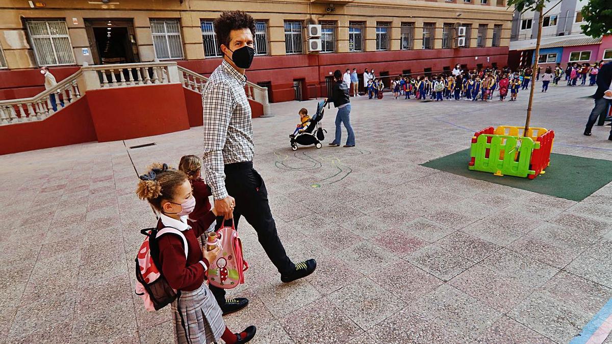 Un padre acompaña a sus hijas, con mascarilla, al colegio durante el pasado curso. | JUAN CARLOS CAVAL