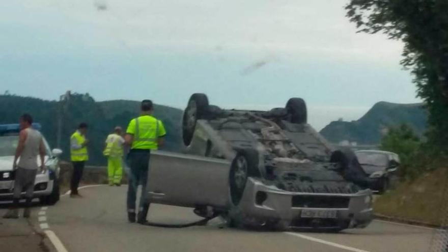 Uno de los vehículos siniestrados, volcado en la carretera.