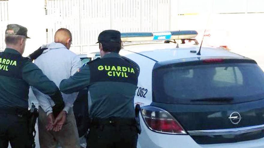 Dos agentes de la Guardia Civil custodian al arrestado.