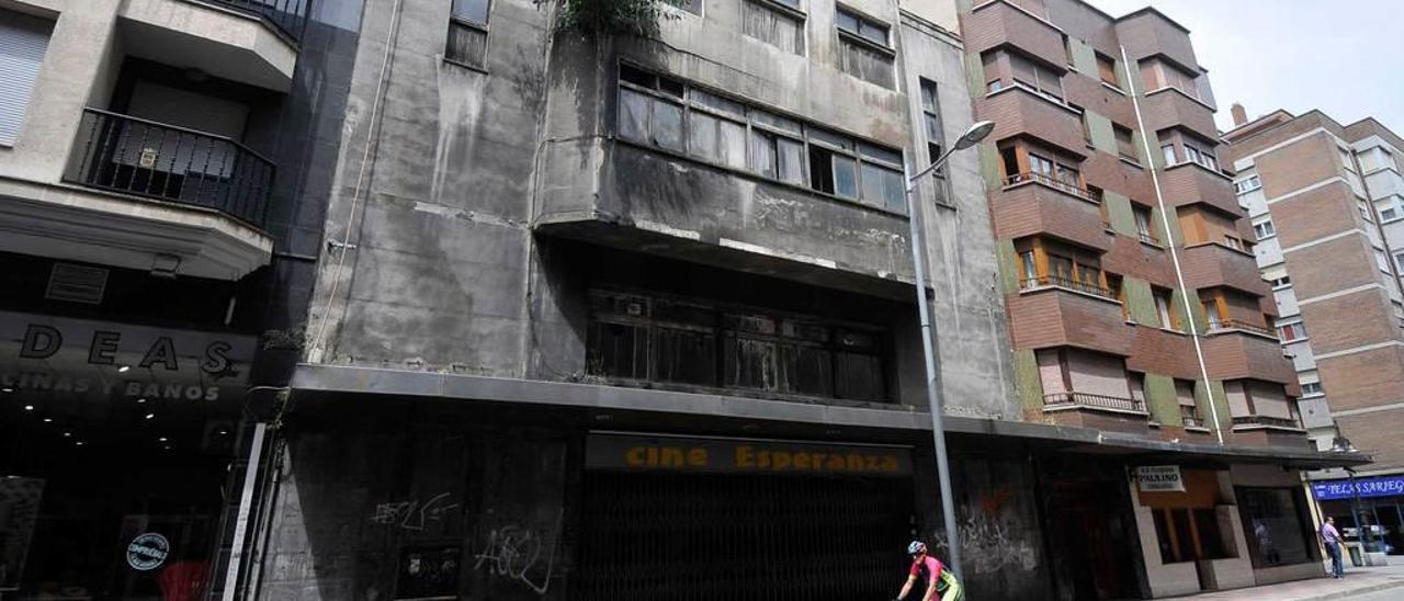 Un ciclista pasa ante el antiguo cine Esperanza de Mieres.