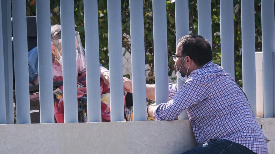 Un residente recibe una visita a través de la valla en una residencia de ancianos.