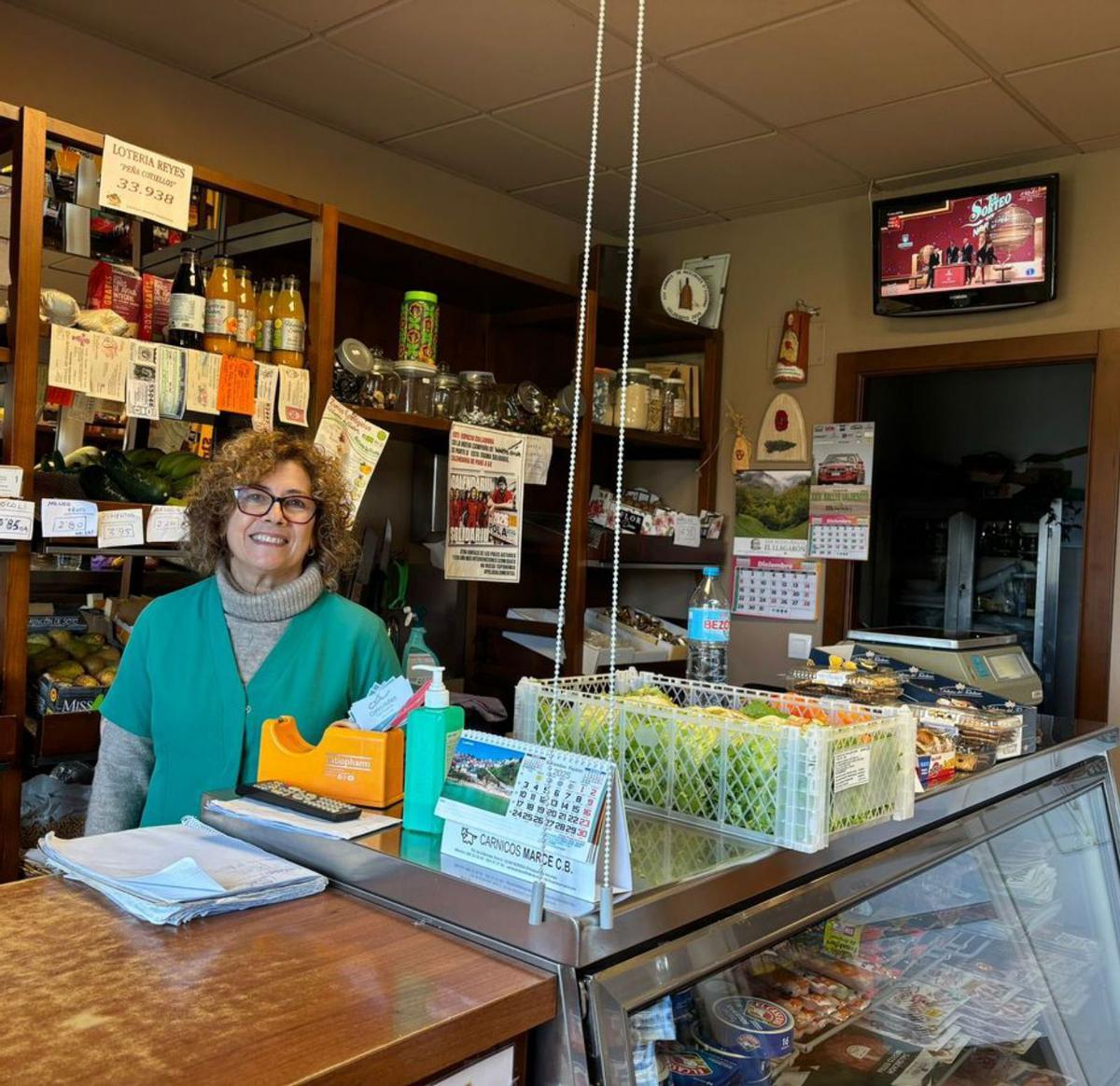 Amparo Palacio, ayer, siguiendo el sorteo en su tienda de alimentos. | S. B.