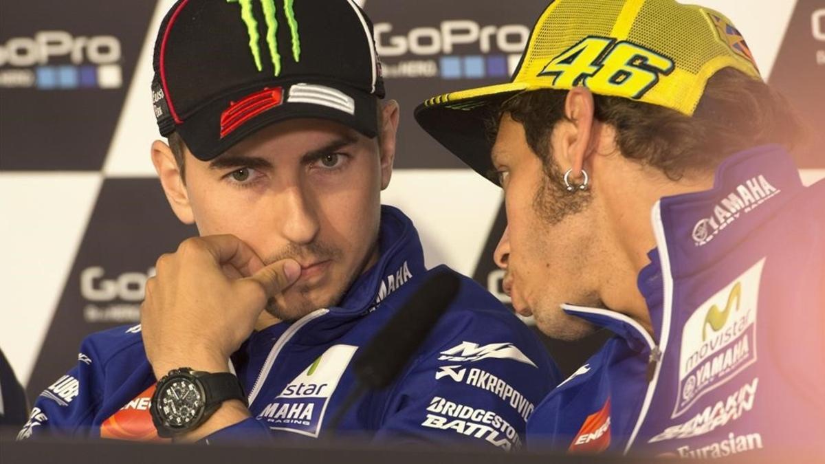 Jorge Lorenzo escucha un comentario que le hace Valentino Rossi.