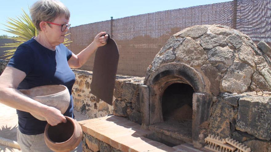 La artesana con varias piezas de barro junto al horno en su casa.