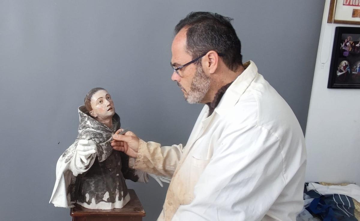 Francisco Naranja trabaja en la restauración de una imagen de un santo en su taller.