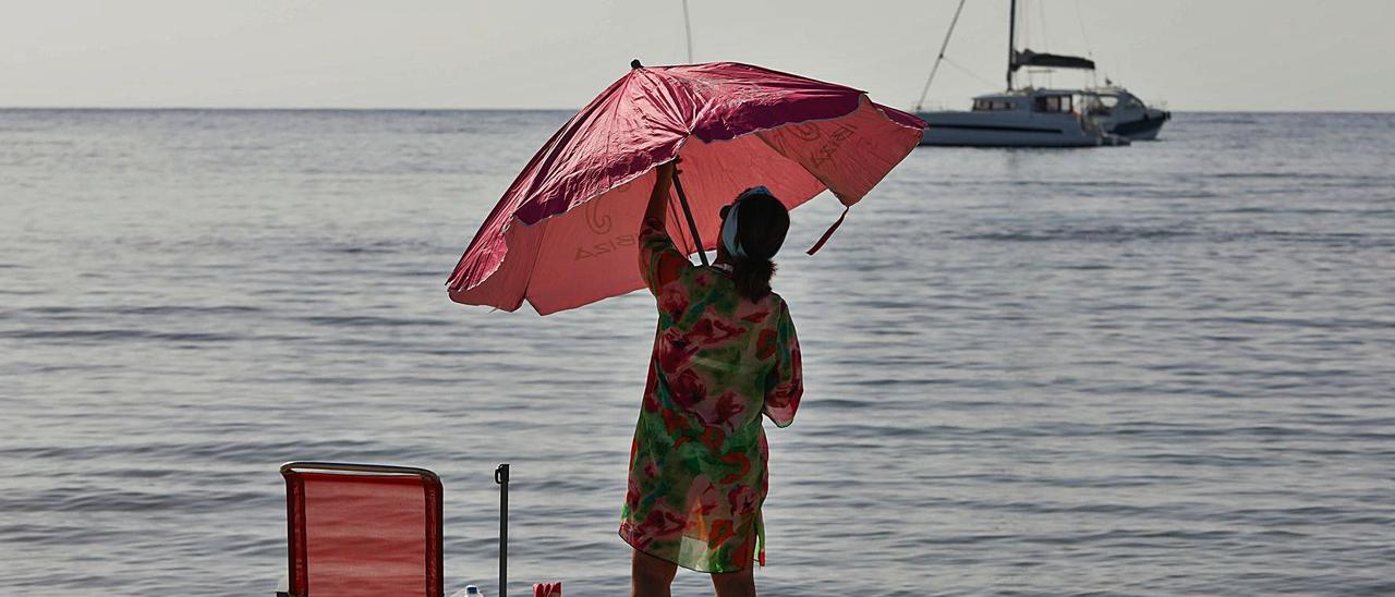 Una turista despliega la sombrilla en una playa de Ibiza. | Zowi Voeten