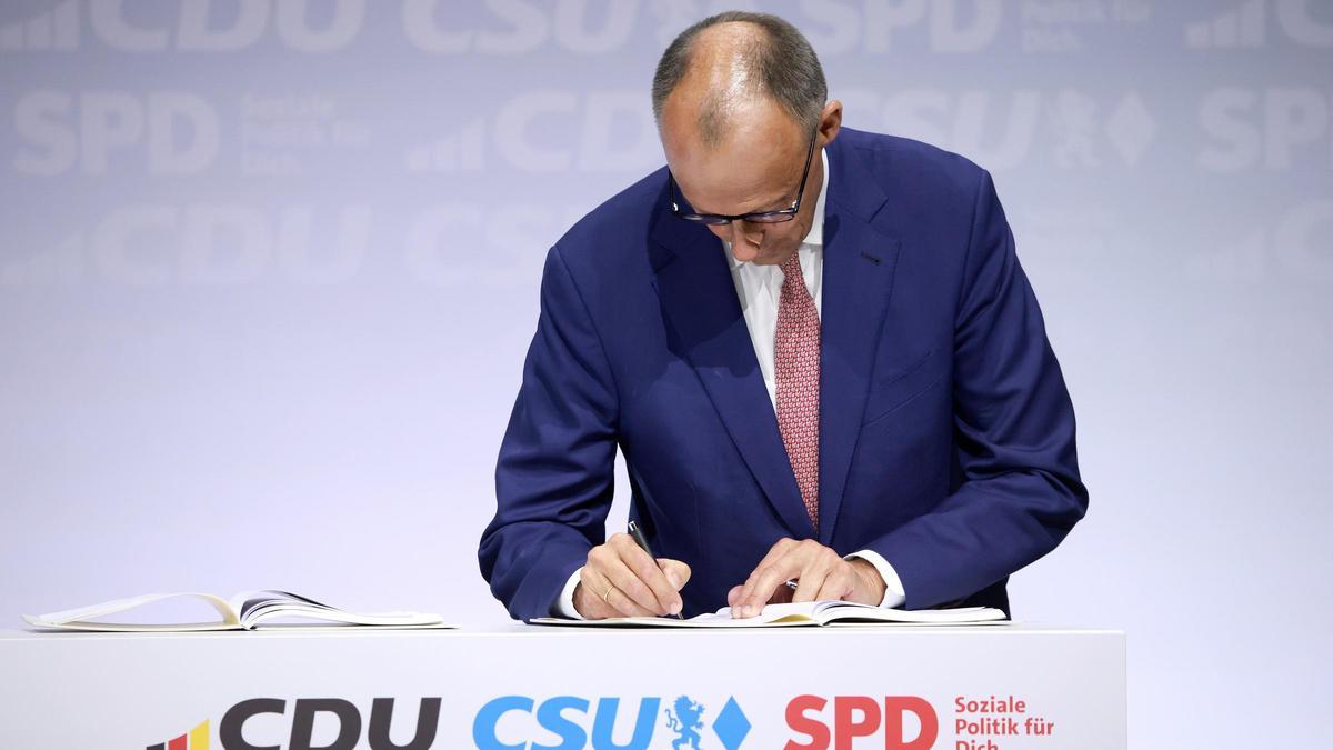 El futuro canciller alemán, Friedrich Merz, firma el acuerdo de gobierno entre CDU, CSU y SPD, este lunes en Berlín.