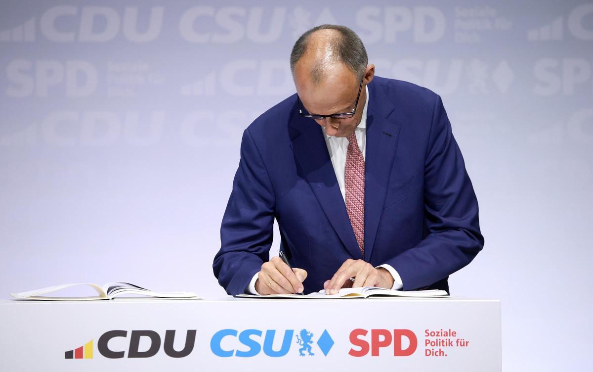 El futuro canciller alemán, Friedrich Merz, firma el acuerdo de gobierno entre CDU, CSU y SPD, este lunes en Berlín.