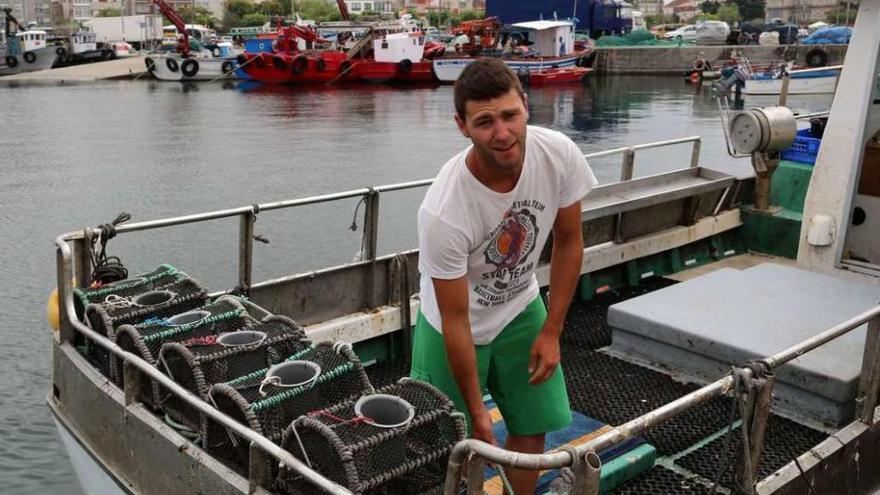 Un joven prepara las nasas en la cubierta de su embarcación, en el puerto grovense. // Muñiz