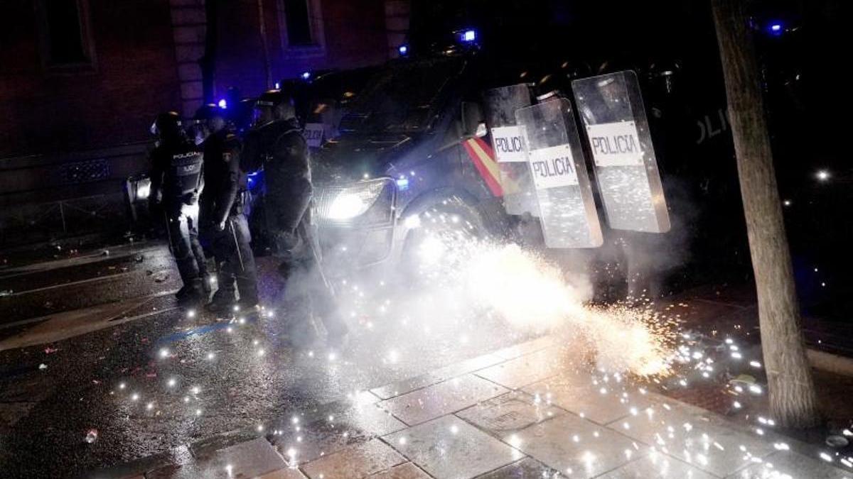 Los manifestantes de la calle Ferraz lanzan petardos y bengalas a los policías antidisturbios.