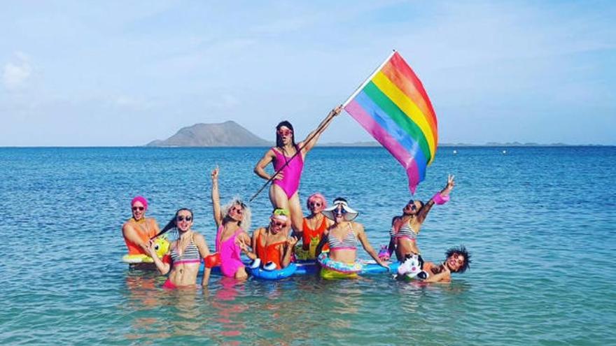 Los asistentes al Rainbow 2016 con la bandera de la tolerancia en la playa.