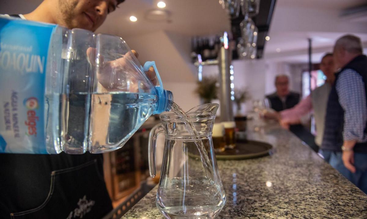 Un hostelero de las callejas de Betanzos llena una jarra con agua embotellada. |   // CASTELEIRO / ROLLER AGENCIA