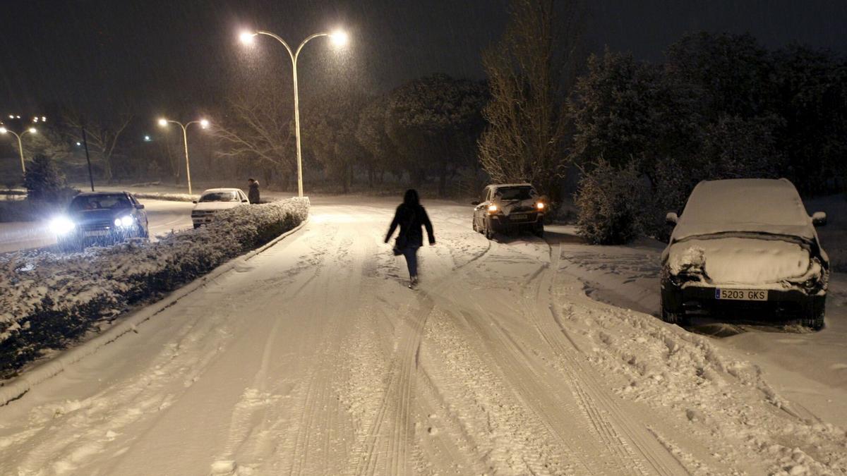 Una mujer camina por una calle de Boadilla del Monte llena de nieve.