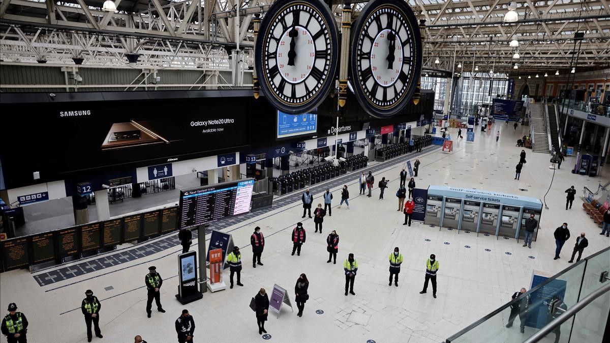 TOPSHOT - Commuters and employees take part in a minute s silence on the first anniversary of the first national Covid-19 lockdown  at Waterloo Station in central London on March 23  2021  (Photo by Tolga Akmen   AFP)