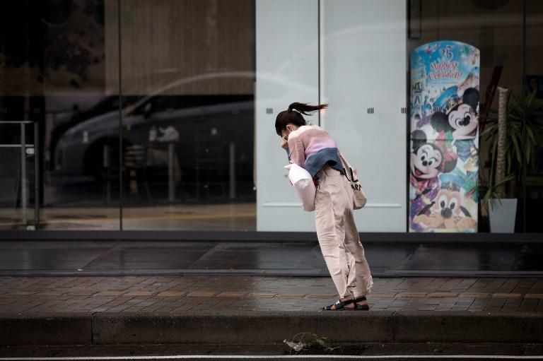 Una mujer intenta caminar contra los fuertes vientos que azotan la ciudad de Kagoshima (Japón) tras el tifón Trami. / AFP PHOTO / Behrouz MEHRI