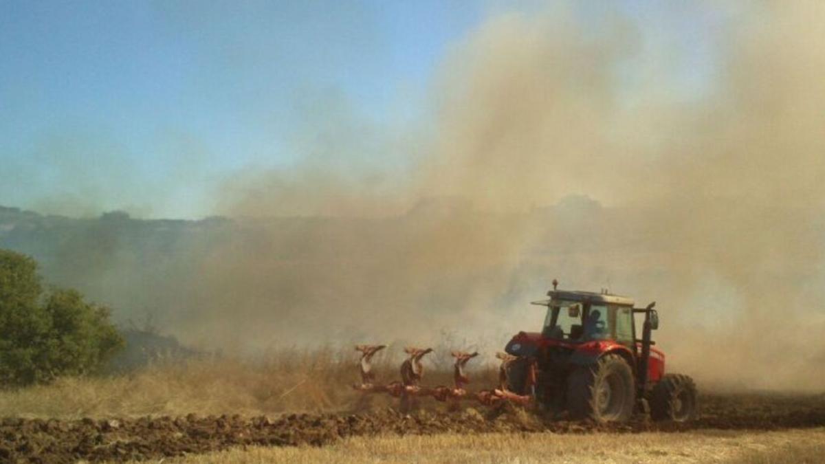 Un tractor haciendo labores de labranza en unas tierras de cultivo en Aragón, con la arena en suspensión por la fuerza del viento. | EL PERIÓDICO