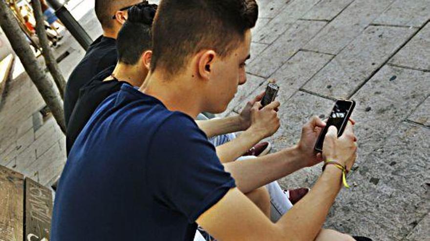 Varios jóvenes observan sus teléfonos móviles en el centro de la ciudad.