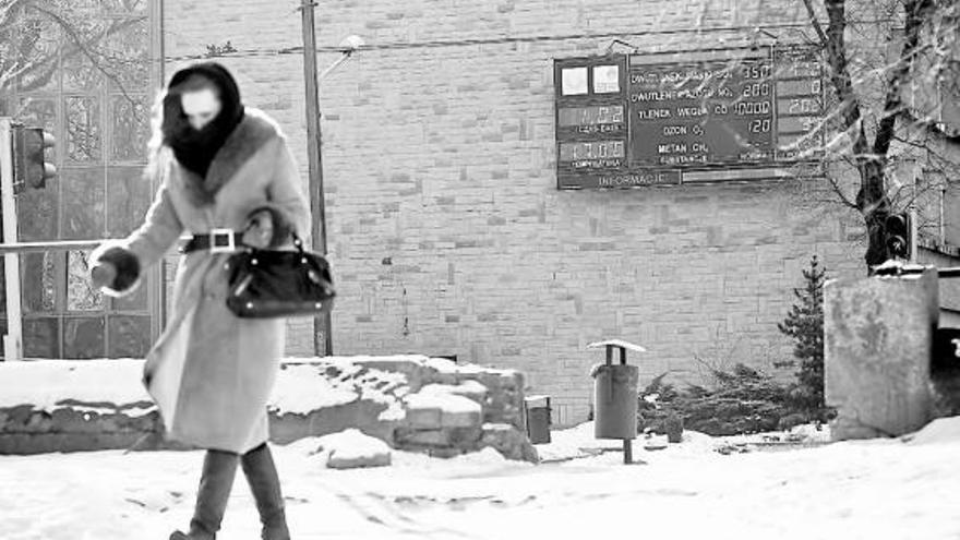 Una mujer muy abrigada camina frente a un tablero que marca 17 grados bajo cero en Lublín, Polonia.