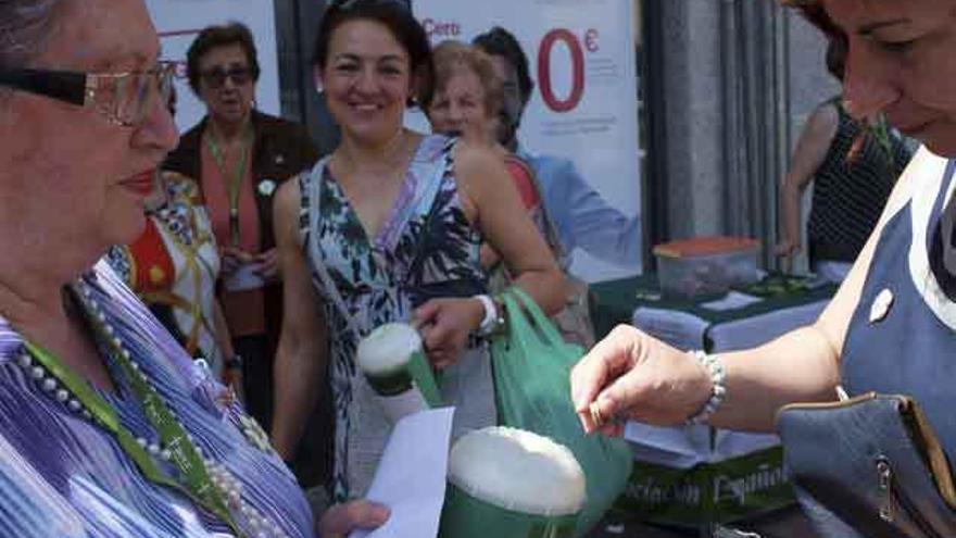 Una mujer deposita unas monedas en la hucha durante la cuestación de la Asociación contra el Cáncer.