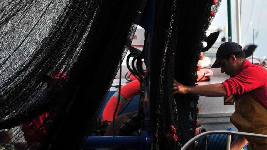 Un mariñeiro carga as redes no barco antes de saír a pescar.