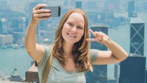 Una chica se hace un selfi haciendo el sígno de victoria.