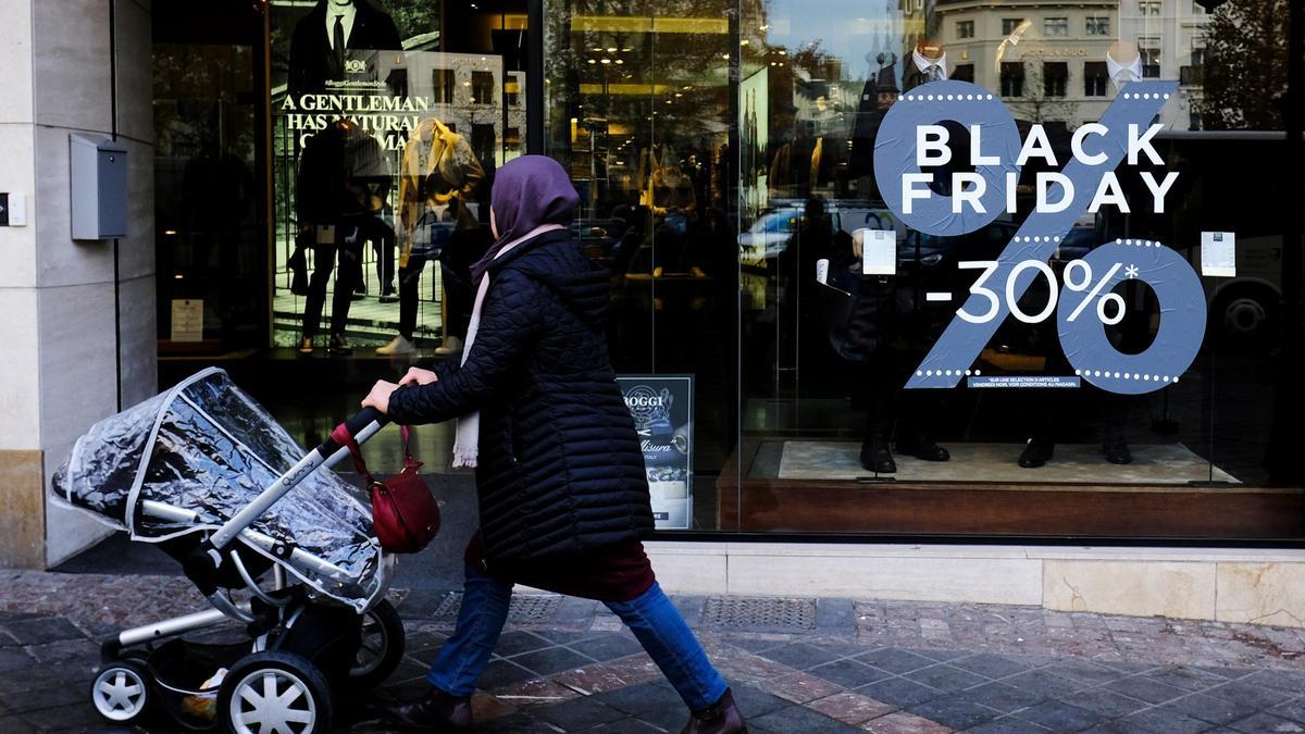 Una mujer pasea por delante de un escaparte que promociona los descuentos del Black Friday.