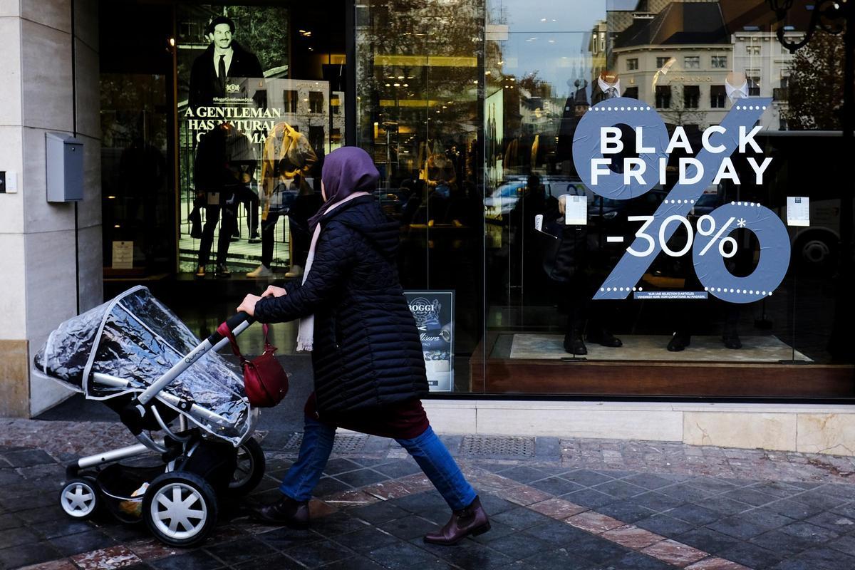 Una mujer pasea por delante de un escaparte que promociona los descuentos del Black Friday.