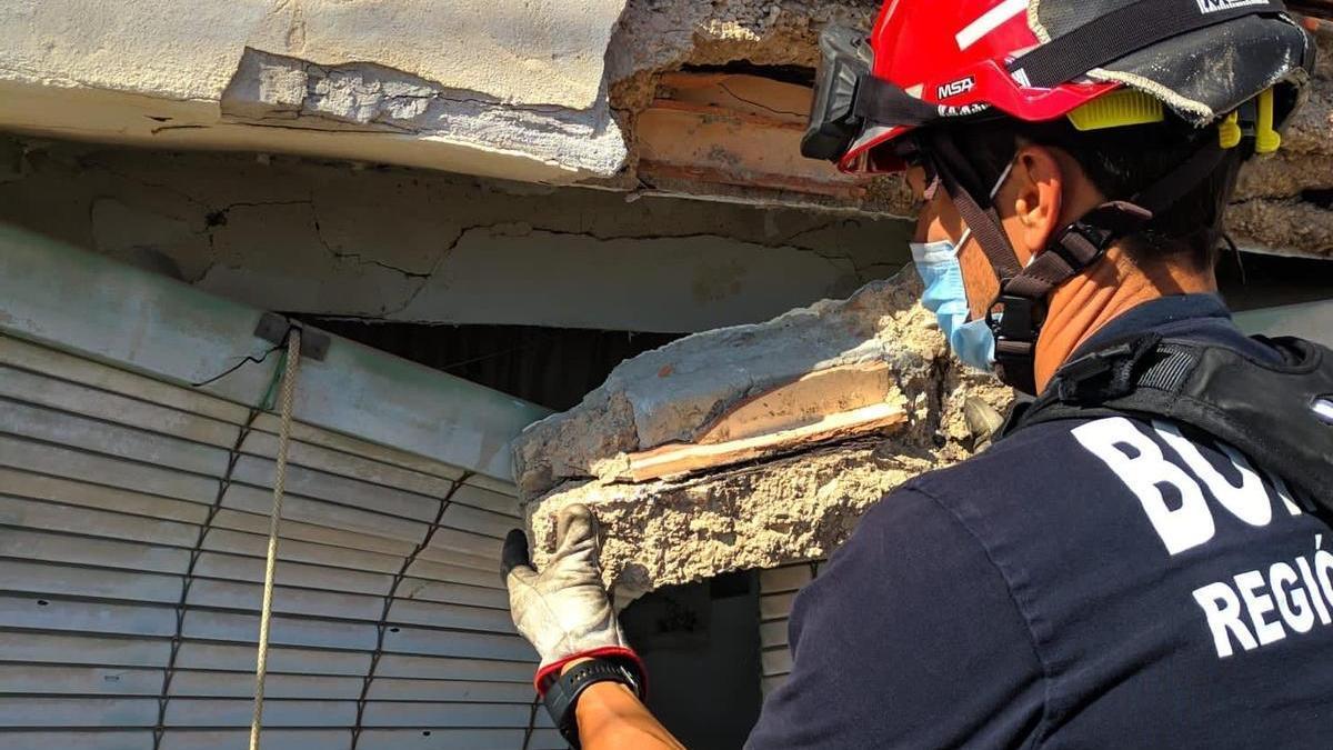 Un bombero recoge parte de la fachada desprendida.