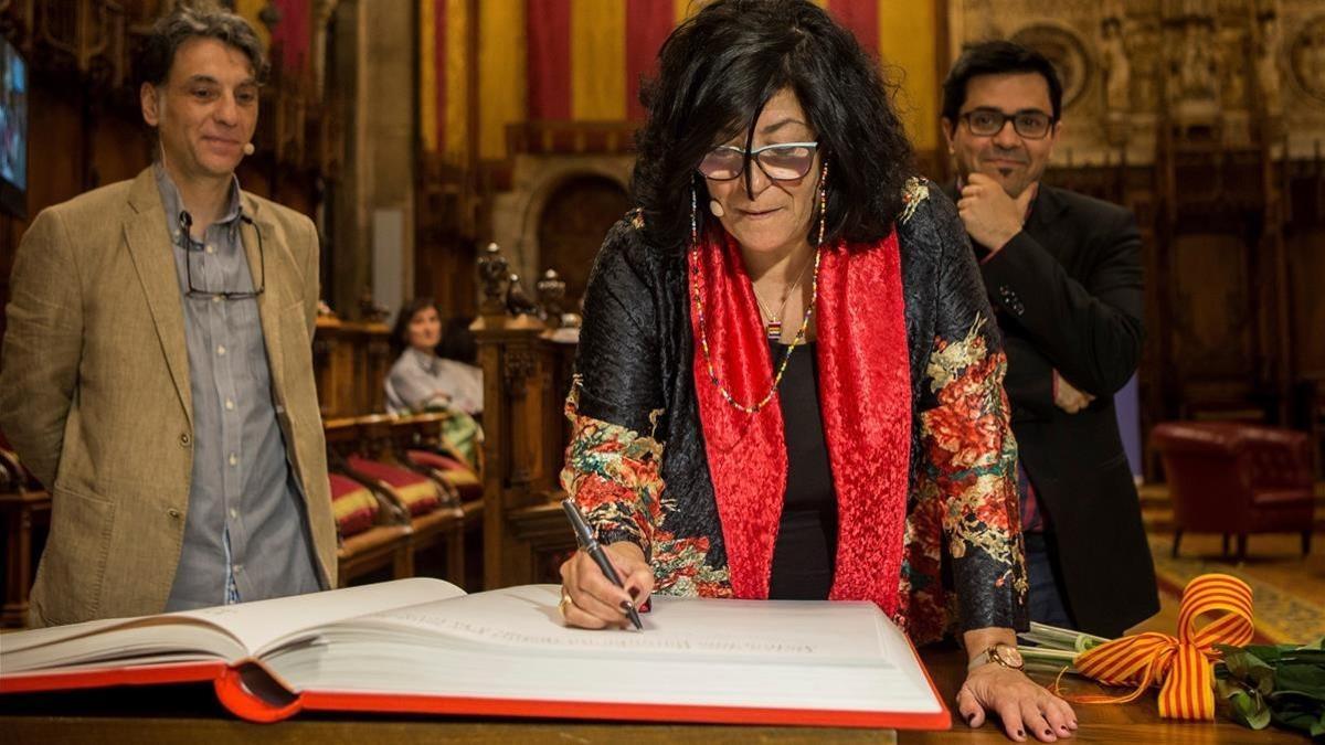 Almudena Grandes, junto al primer teniente de alcalde Gerardo Pisarello, firma en el libro de honor.