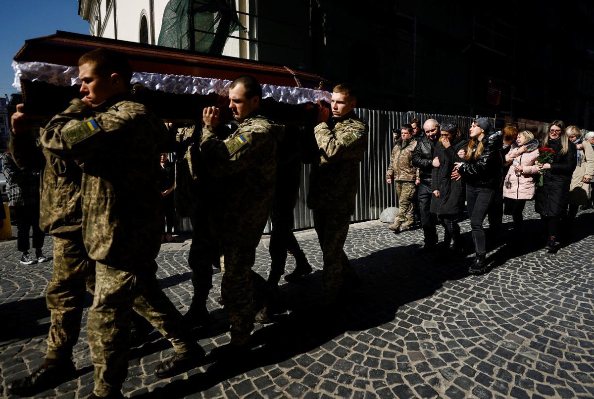 Soldados llevan el ataúd de su compañero Denys Snihur, de 25 años, un guardia fronterizo convertido en soldado, muerto por los bombardeos rusos en la ciudad norteña de Ovruch, mientras sus padres caminan detrás, después del servicio conmemorativo durante su funeral en las afueras de Saints Peter and Paul Garrison. Iglesia, en Lviv, Ucrania