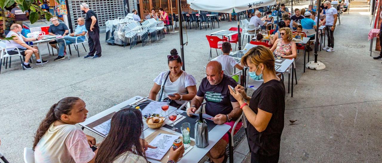 Una camarera atiende una mesa en una terraza de un establecimiento de Benidorm. | DAVID REVENGA