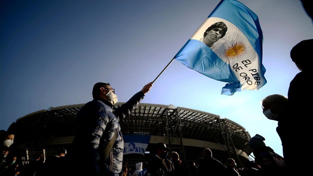 Un hombre agita una bandera argentina con el rostro de Maradona en Nápoles.